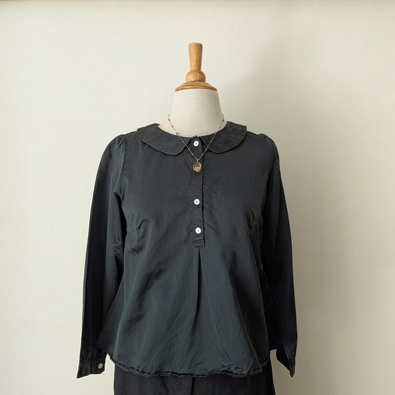 Dark green blouse on a mannequin against a plain background