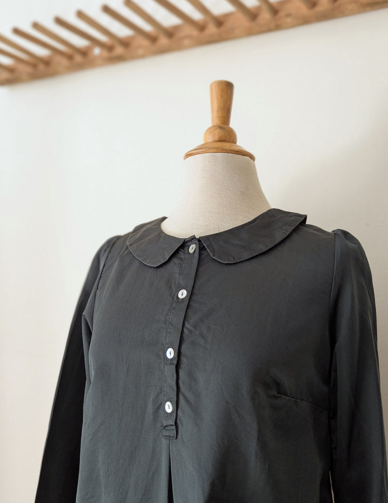 Dark green blouse on a mannequin against a plain background