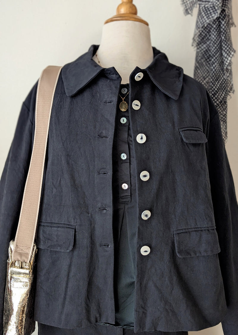 Black jacket with button details on a mannequin against a neutral background