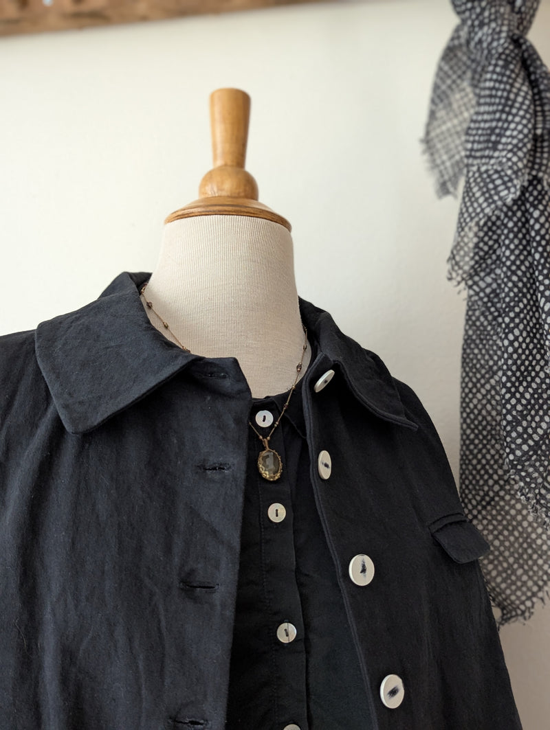 Black coat on a mannequin with a textured wall background