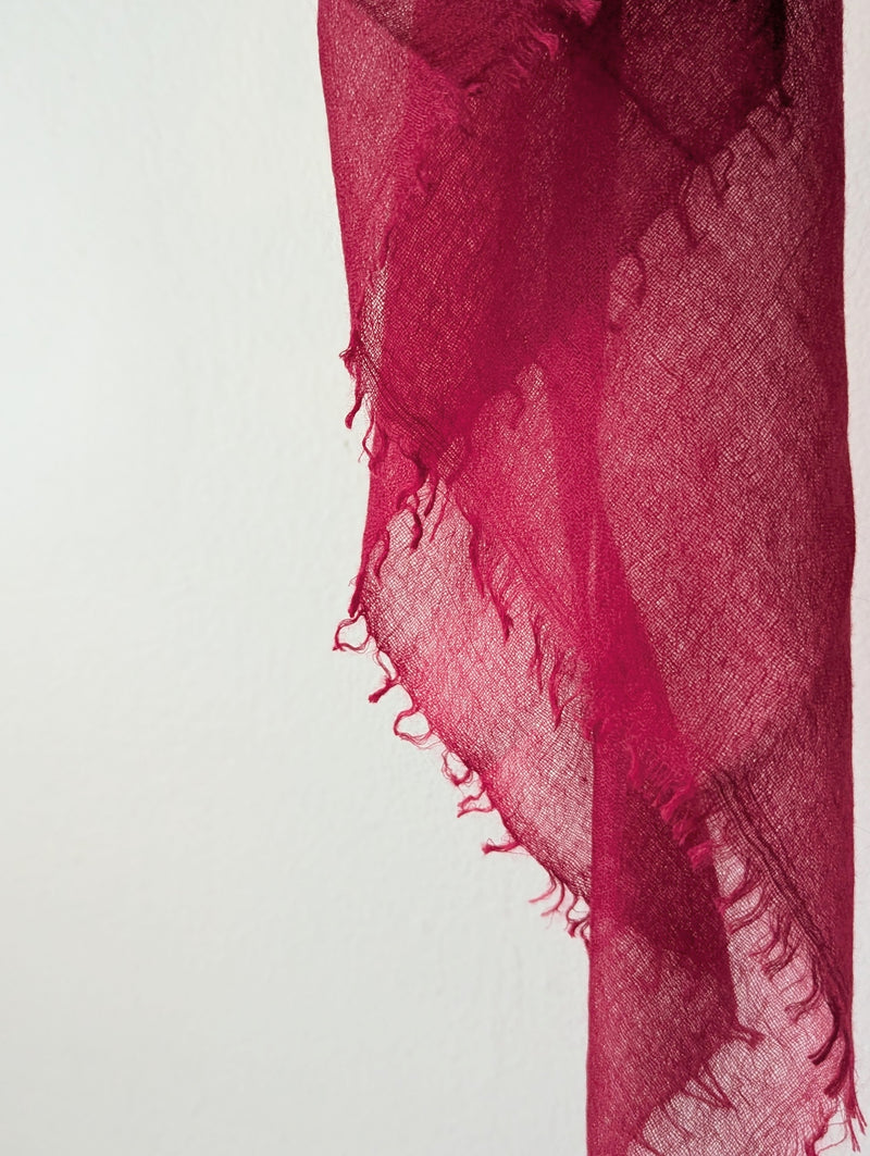 Red scarf with frayed edges on a light gray background