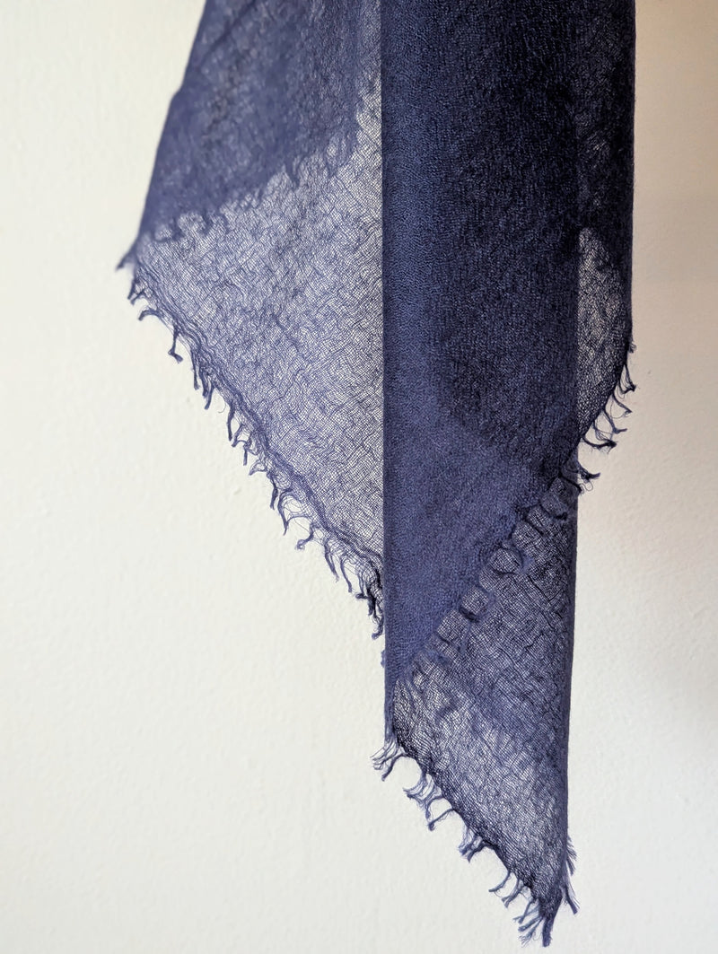 Navy blue scarf with frayed edges on a light beige background