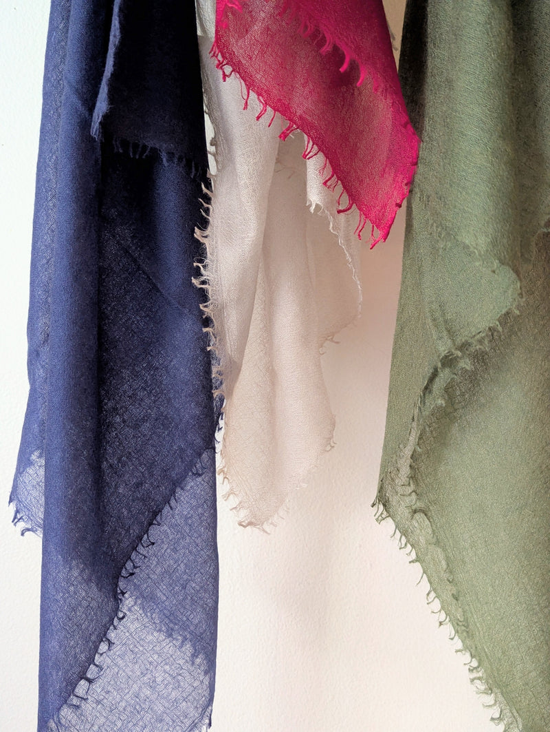 Four scarves in blue, pink, white, and green on a white background