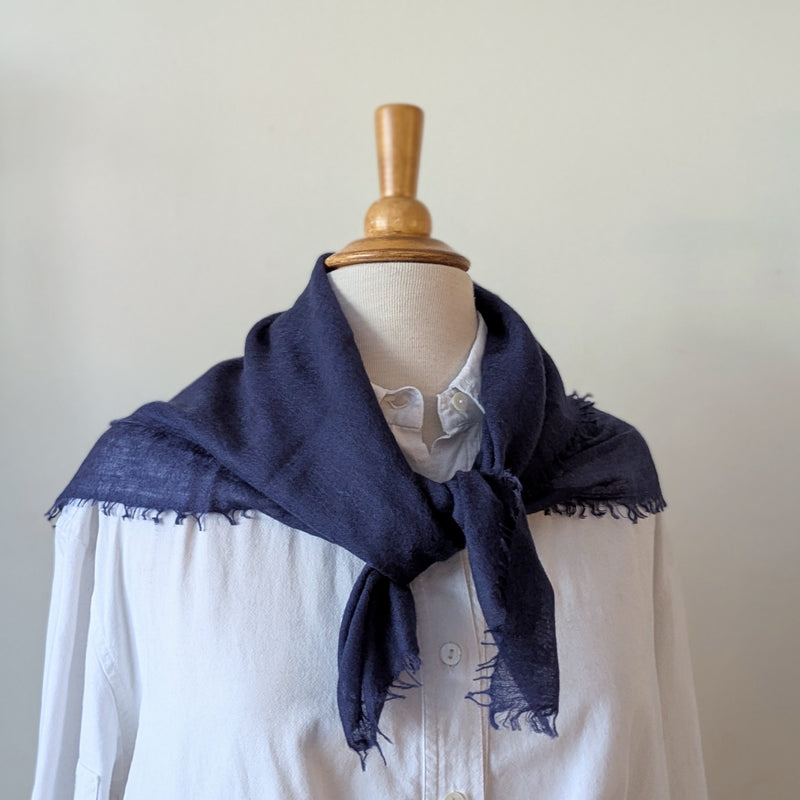 Navy blue scarf draped over a white shirt on a mannequin against a plain background