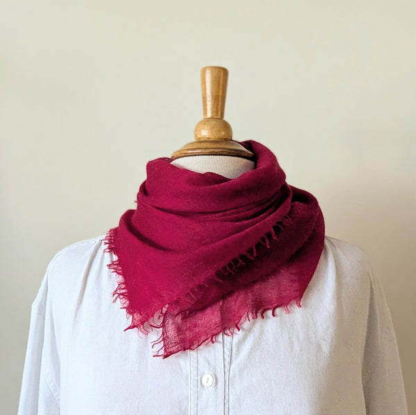 Mannequin wearing a white shirt with a red scarf draped over it against a plain background