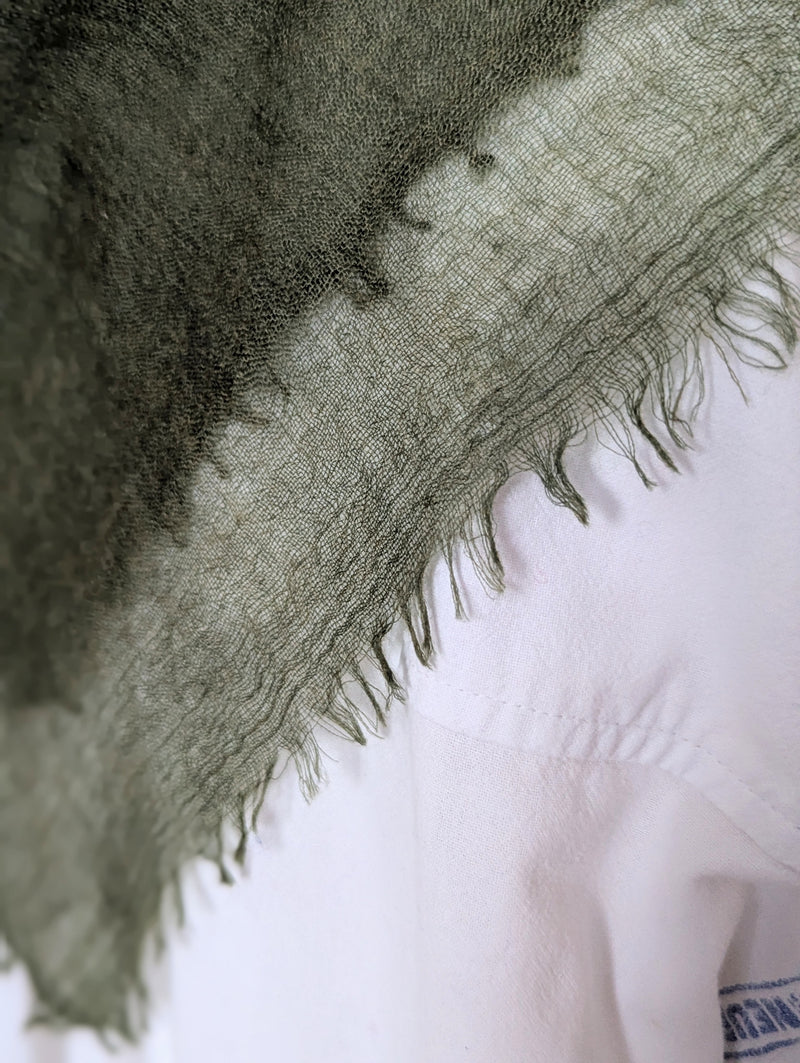 Close-up of a sheer cashmere scarf with frayed edges on a white background