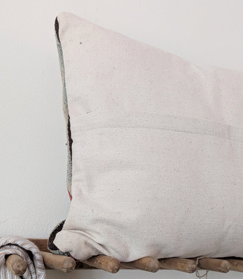 Beige pillow on a wooden rack against a white wall