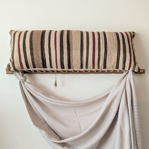 Striped pillow on a wall-mounted shelf with draped fabric below