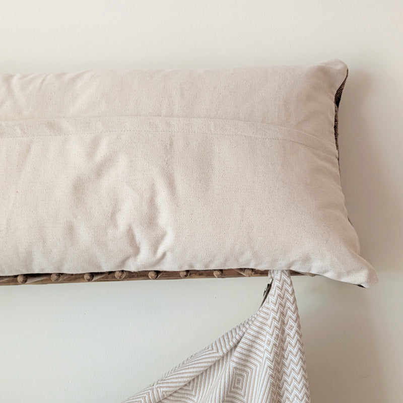 Back of a striped pillow on a white surface with a folded blanket underneath