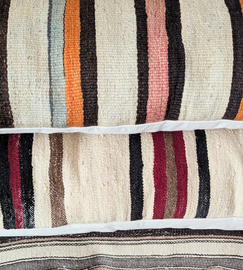 Striped pillows with multicolor patterns stacked on each other.