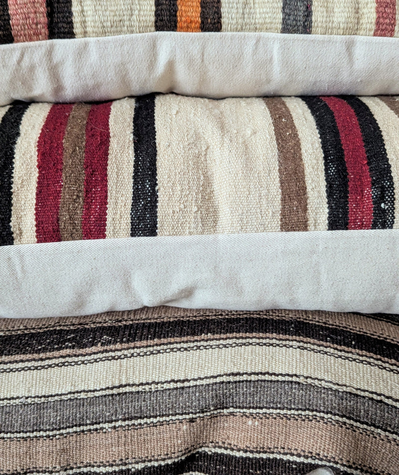 Striped pillows with a pattern of black, red, and beige stripes on a white background.