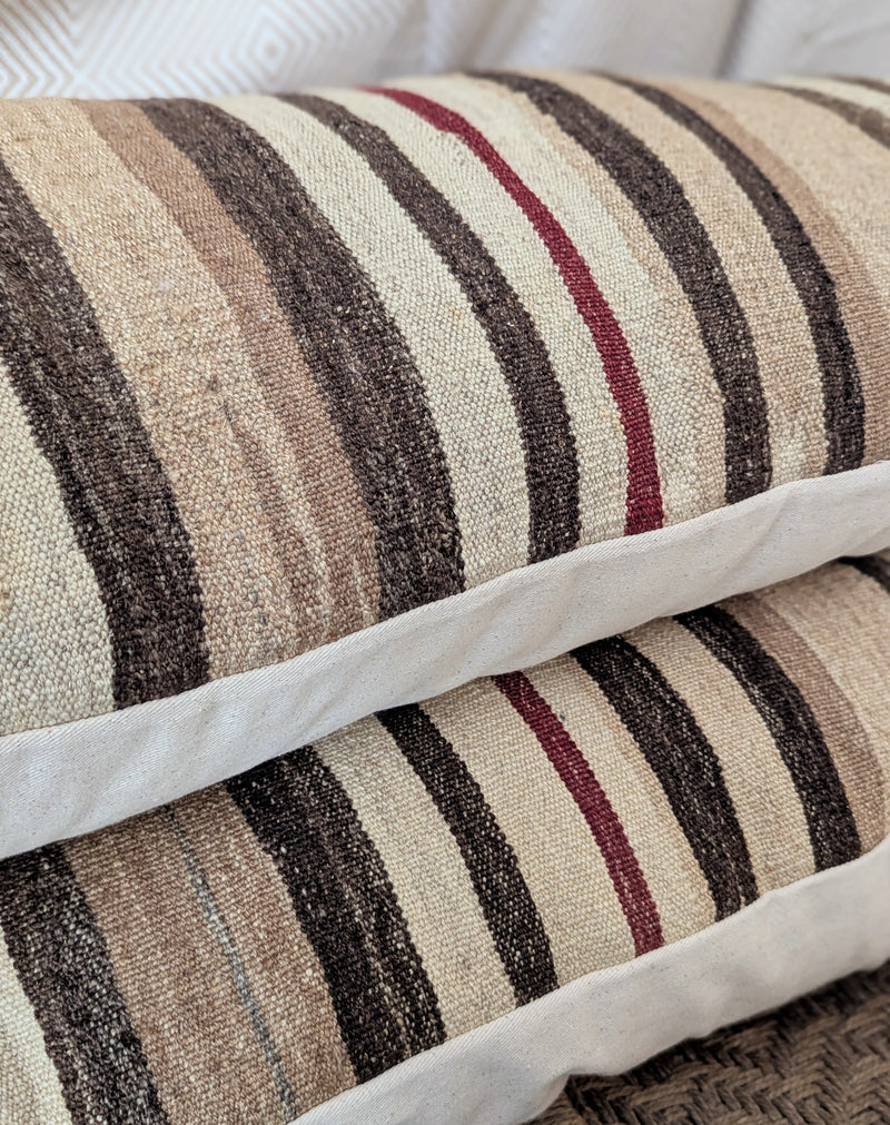 Striped pillow with brown, beige, and red colors on a white background