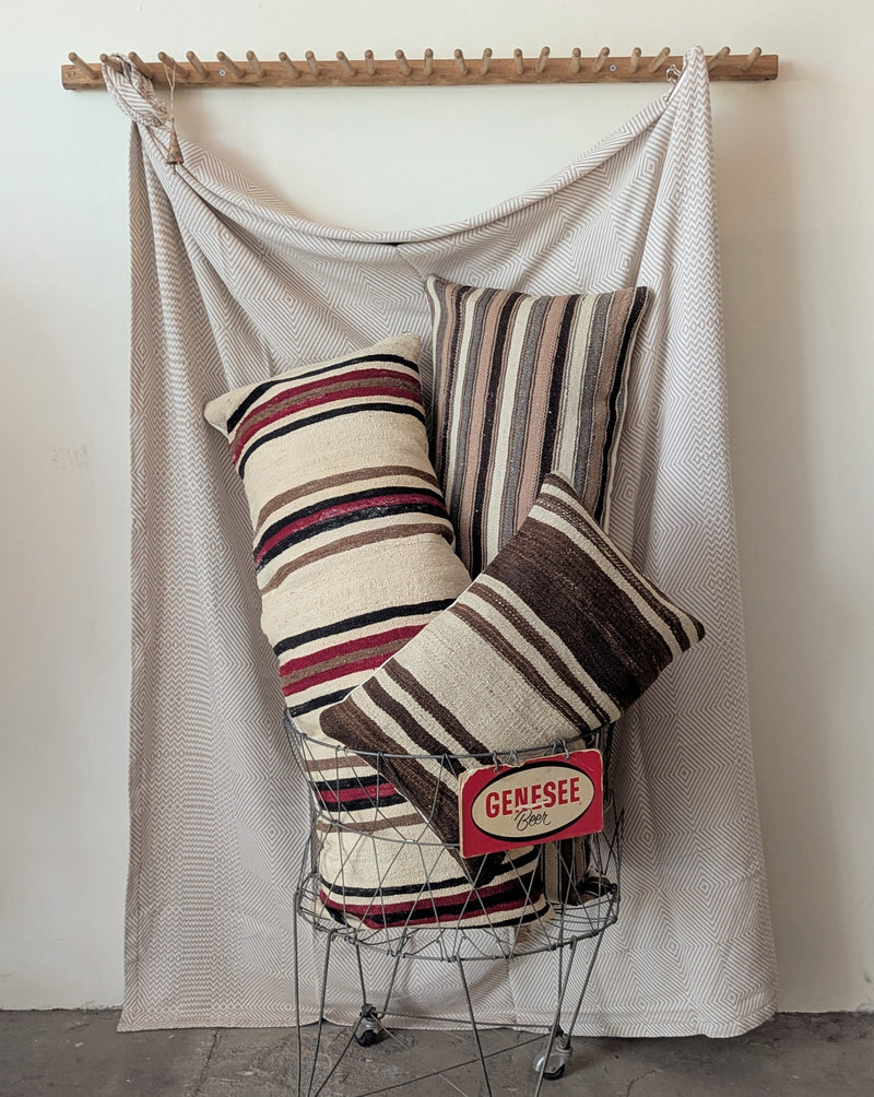 Striped pillows on a wire basket with a white and beige blanket the background
