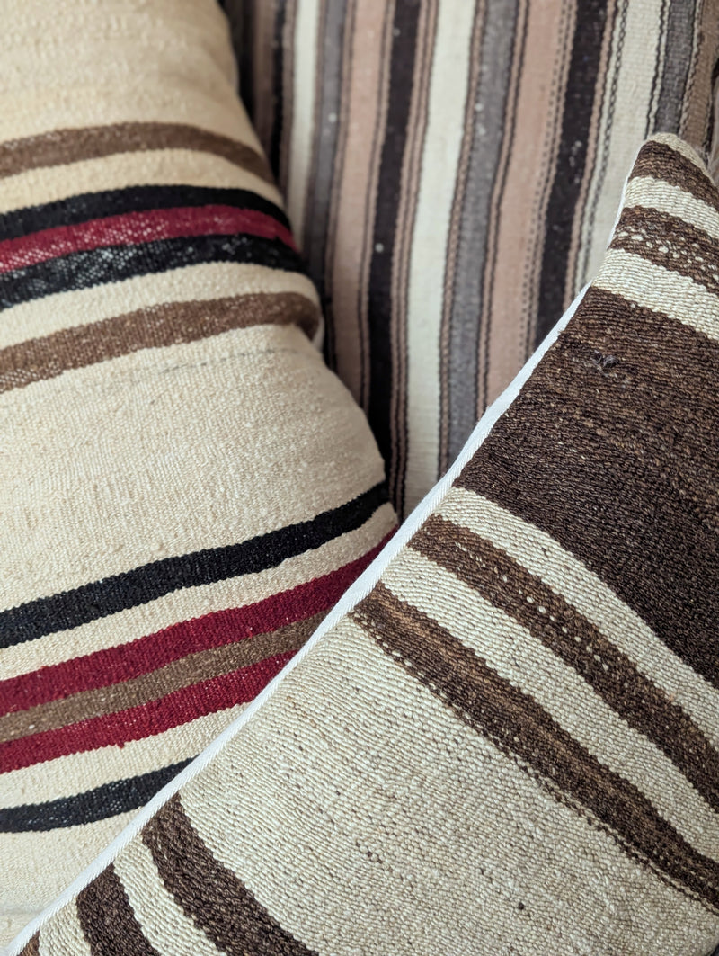 Close-up of striped pillows with brown, beige, and red colors.