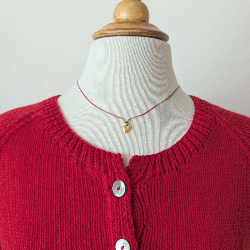 Necklace with orange cord with a blue bead and a gold heart pendant 
