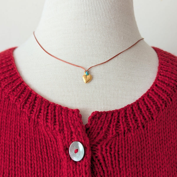 Necklace with orange cord with a blue bead and a gold heart pendant 