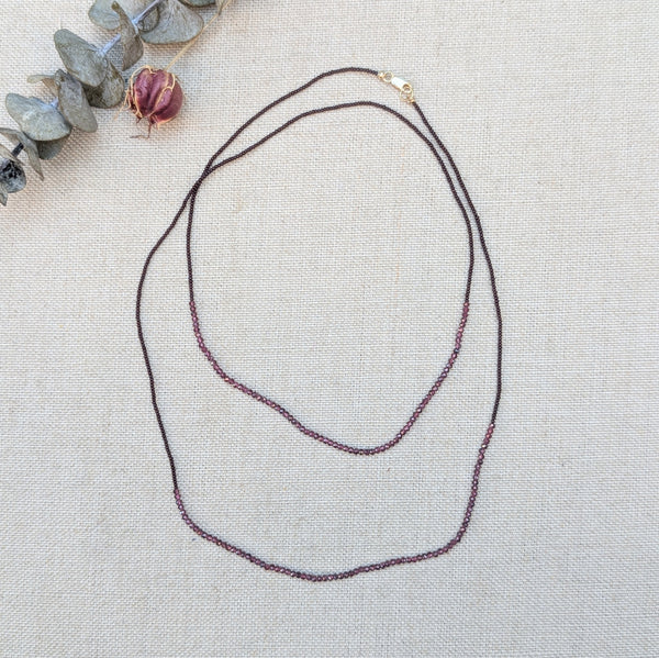Necklace with small ruby beads on a textured surface with decorative elements