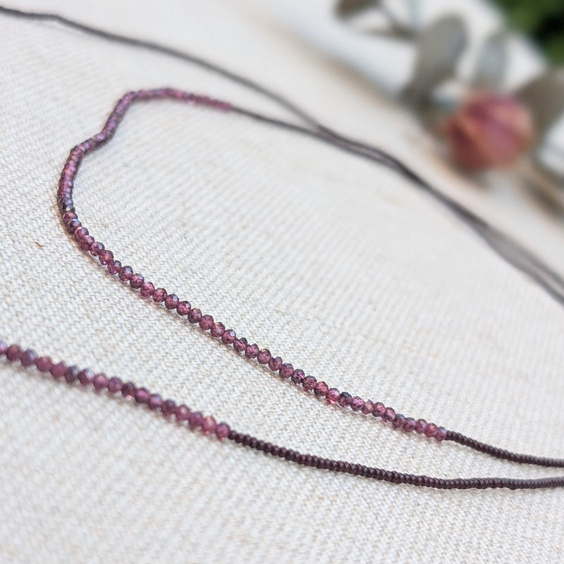 Ruby beaded necklace on a textured white surface