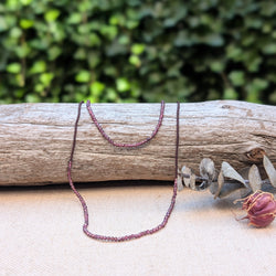 Necklace with small ruby beads on a piece of wood with a natural background