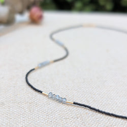 Necklace with black and grey beads and gold accents on a textured surface