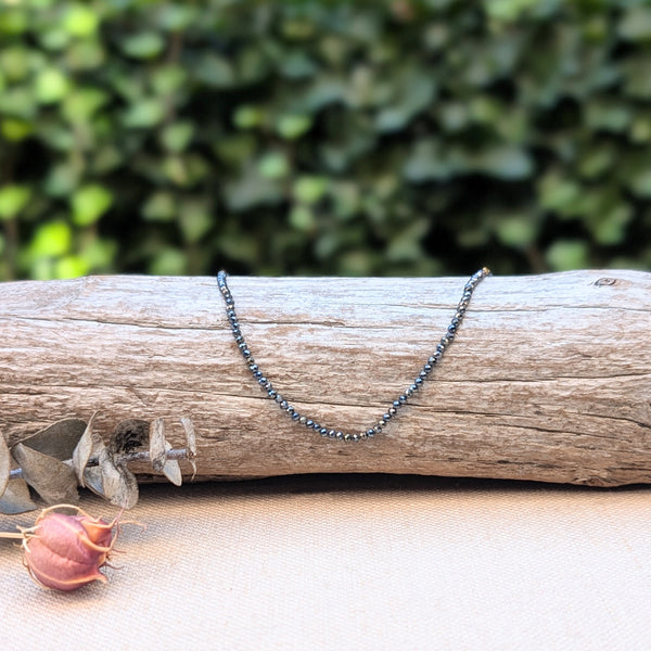 Necklace with small beads on a wooden log with a natural background