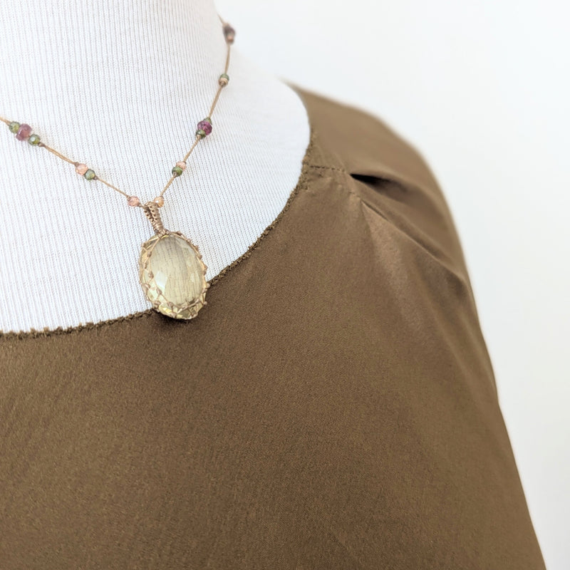 Tobacco brown draped silk blouse from Susanne Bommer on a mannequin with a necklace featuring a large gemstone pendant.