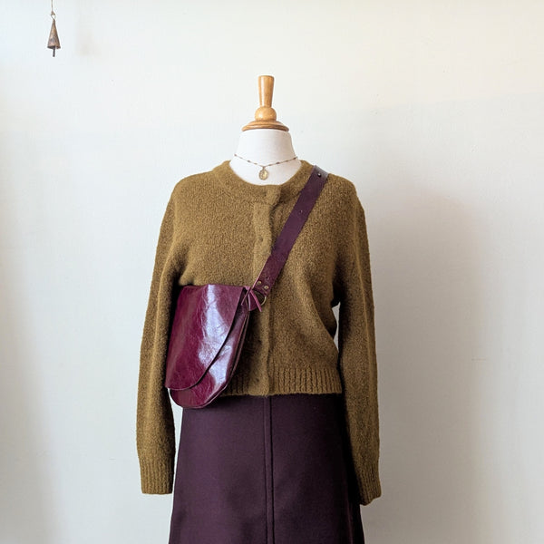 Mannequin wearing a brown sweater and purple skirt with a Stitch and Tickle Short Passy Bag in Wine against a white background