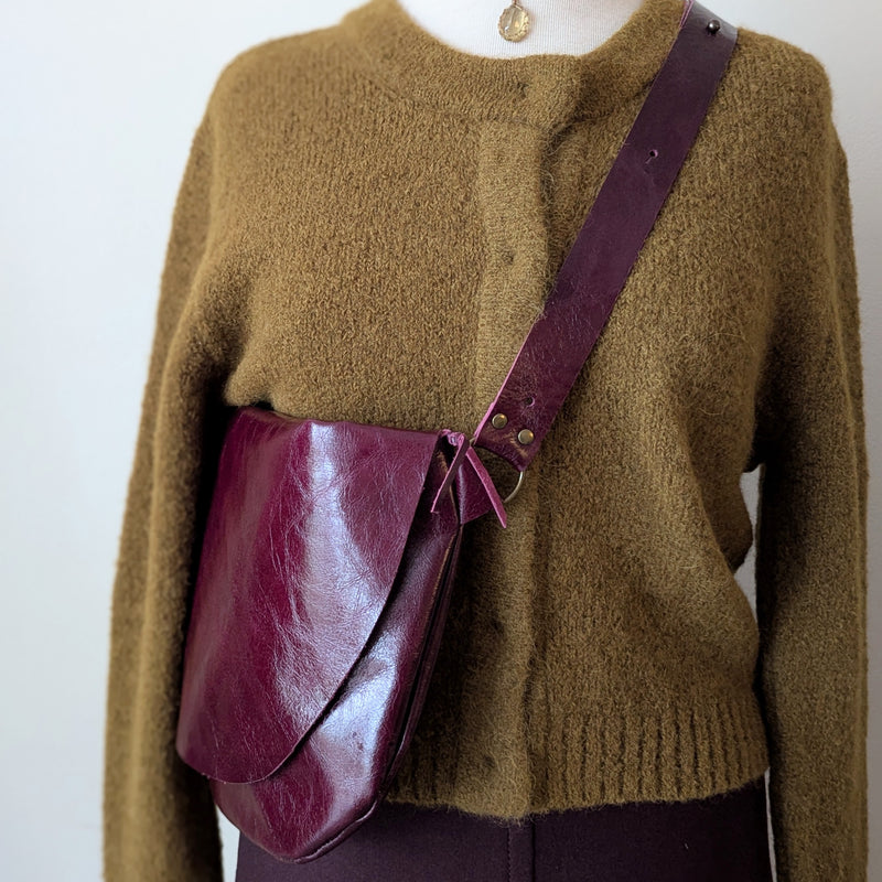 Mannequin wearing a brown sweater with a Stitch and Tickle Short Passy Bag in Wine over one shoulder against a white background