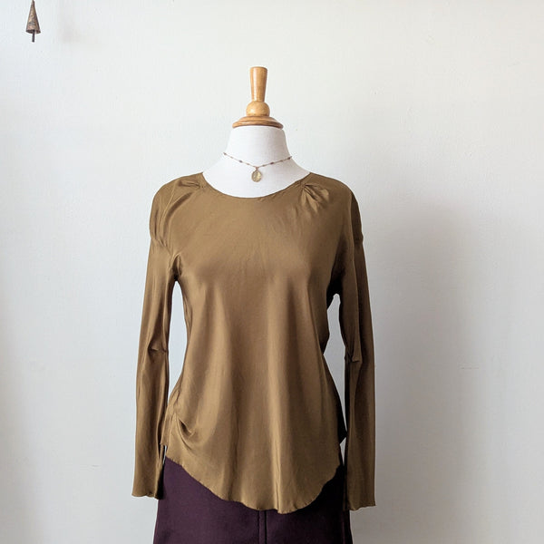 Mannequin wearing a golden brown Susanne Bommer draped silk top and purple skirt against a white background