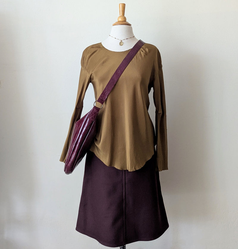 Tobacco brown draped silk blouse and maroon wool skirt from Susanne Bommer on a mannequin with a red Stitch & Tickle bag