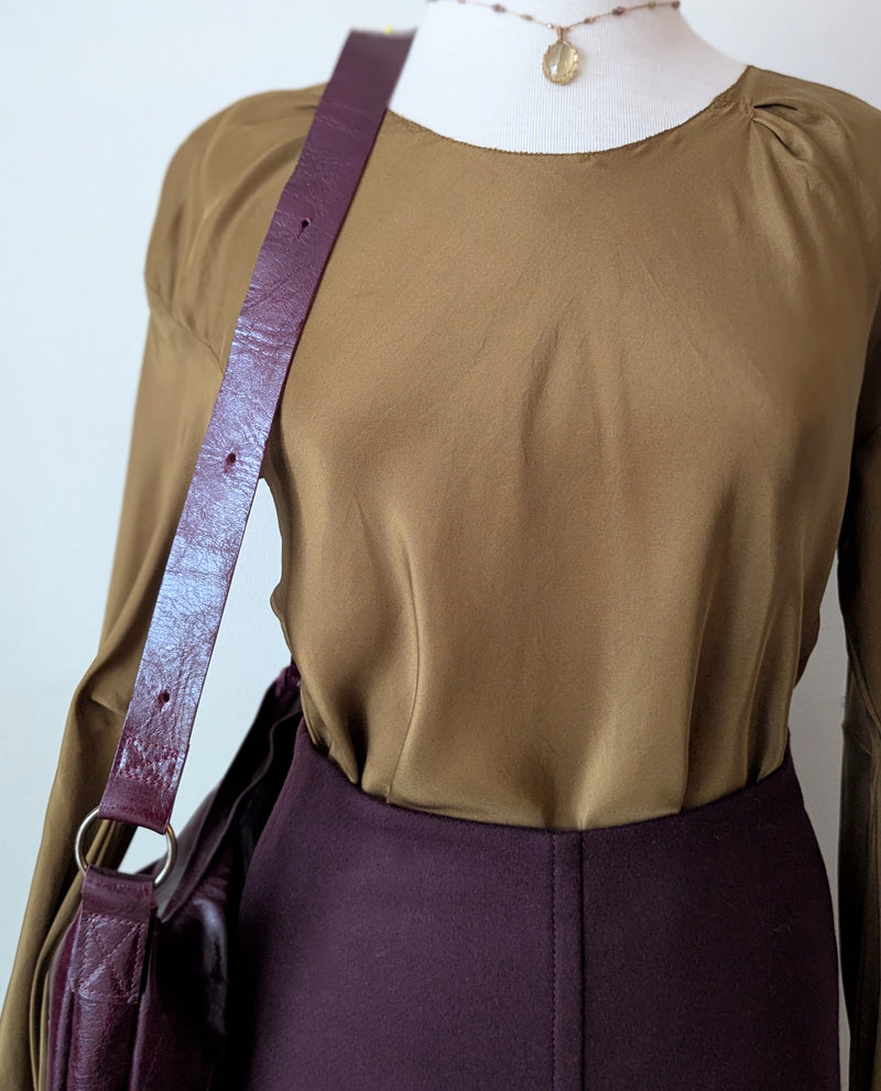 Tobacco brown draped silk blouse and maroon wool skirt from Susanne Bommer on a mannequin with a red Stitch & Tickle bag