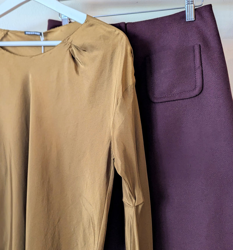 Brown silk top and maroon wool skirt hanging on a rack