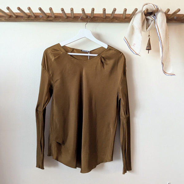 Susanne Bommer draped silk top in tobacco hanging on a wooden rack with a moismont white scarf.