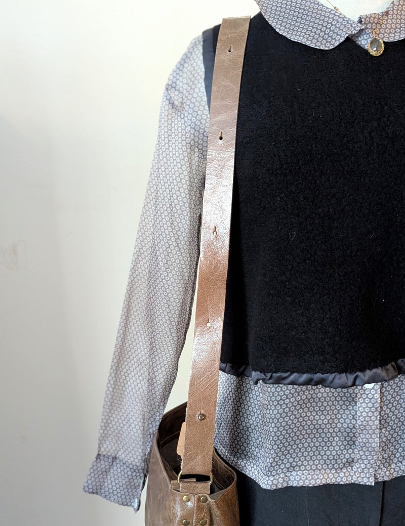 Person wearing a black vest over a patterned shirt with a Stitch and Tickle Everyday Carryall bag in Chai 