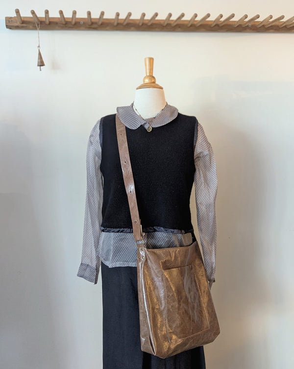 Mannequin wearing a black top, sheer long-sleeve shirt, dark pants, and Stitch and Tickle Everyday Carryall bag in Chai  against a white background.
