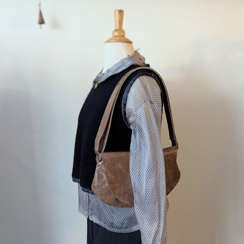 Mannequin wearing a black top, gray patterned shirt, and aStitch and Tickle Passito bag in Chai  against a plain background