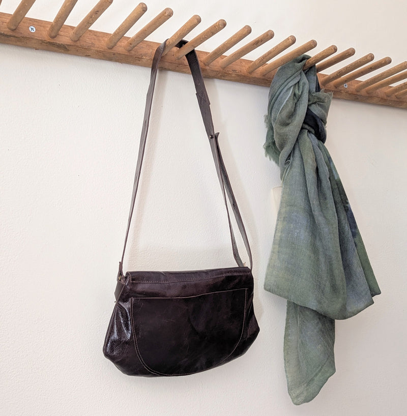 Stitch & Tickle Passito leather bag in Espresso hanging on wooden rack with an Oats and Rice wispy scarf