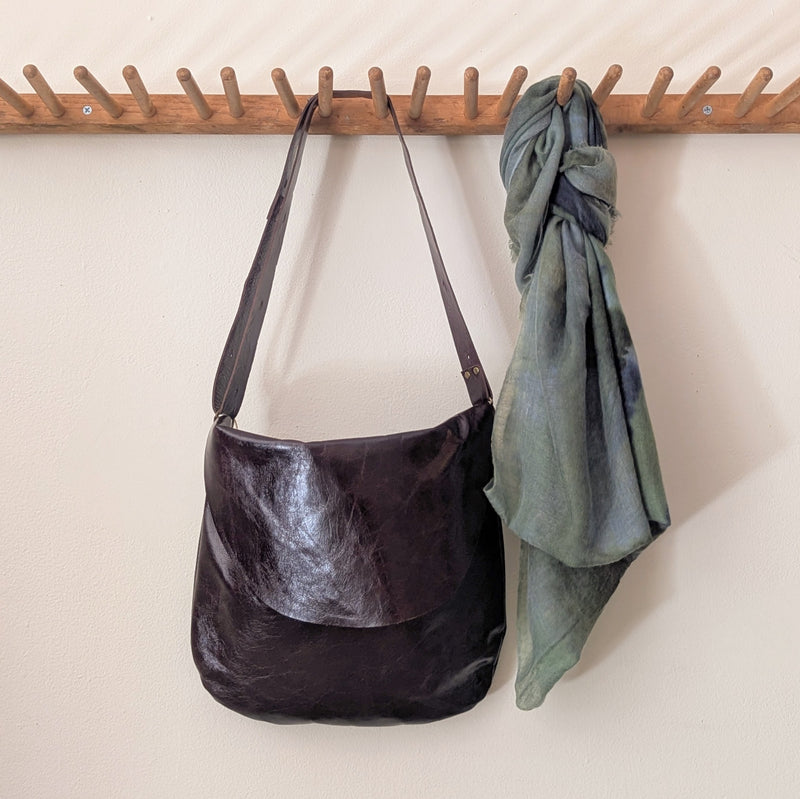 Stitch and Tickle Passy Bag in Espresso and green fabric draped over a wooden rack against a white wall.