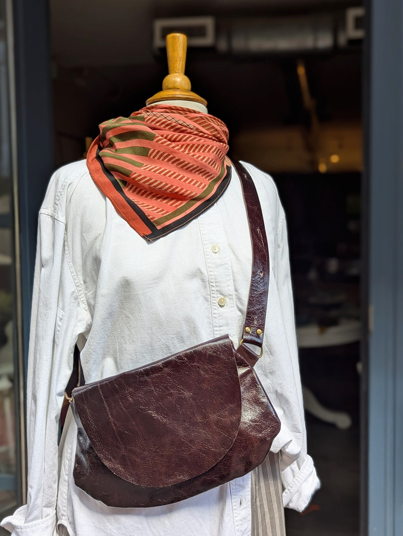 Mannequin wearing a white shirt with aStitch & Tickle Passito leather bag in Espresso and a patterned orange scarf.