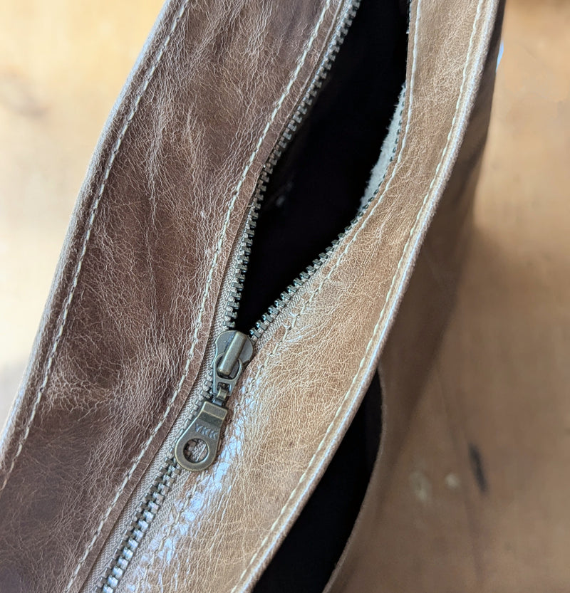 Close-up of the Stitch and Tickle Everyday Carryall bag in Chai zipper on a wooden surface