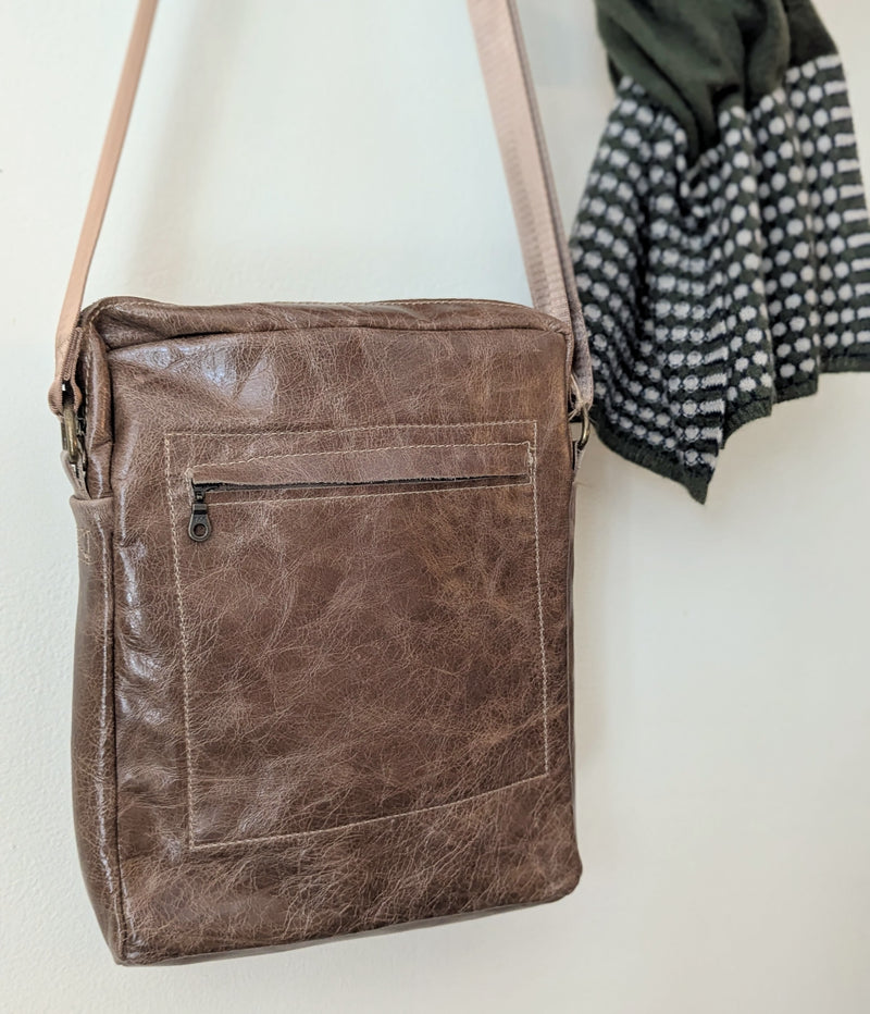 Stitch & Tickle Bourvil Bag in Chai  on a white surface with a piece of clothing in the background