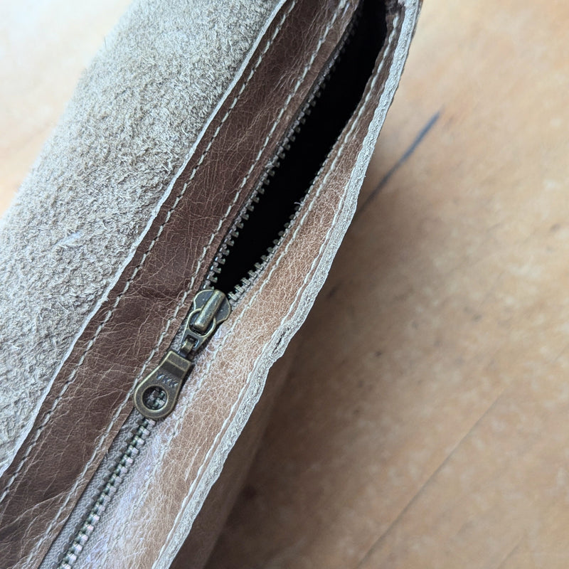 Close-up of the Stitch & Tickle mini messenger bag in Chai's zipper on a wooden surface