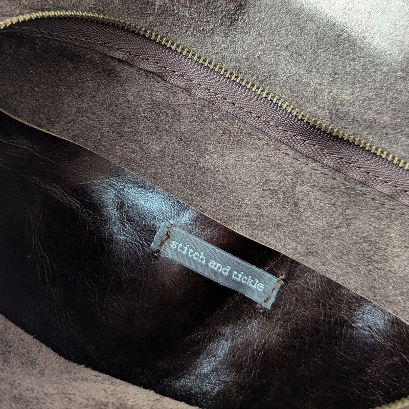 Close-up of a Stitch & Tickle Passito leather bag in Espresso with a 'stitch and tickle' label.