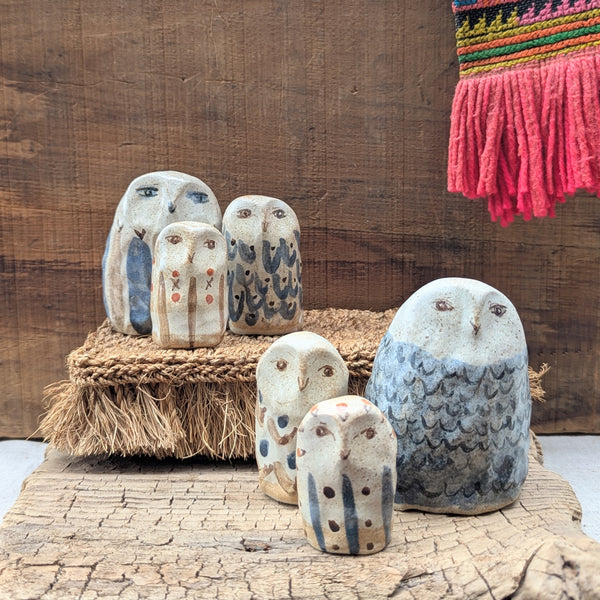 Set of ceramic owl sculptures on a wooden surface with a rustic background