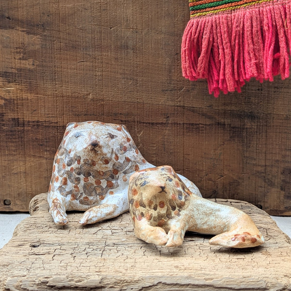 Two ceramic lion figurines on a wooden surface with a rustic background.
