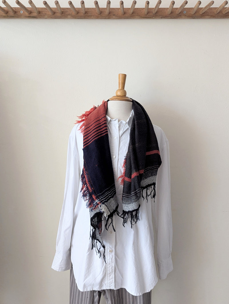 Mannequin wearing a white shirt with a black and red plaid scarf against a plain background