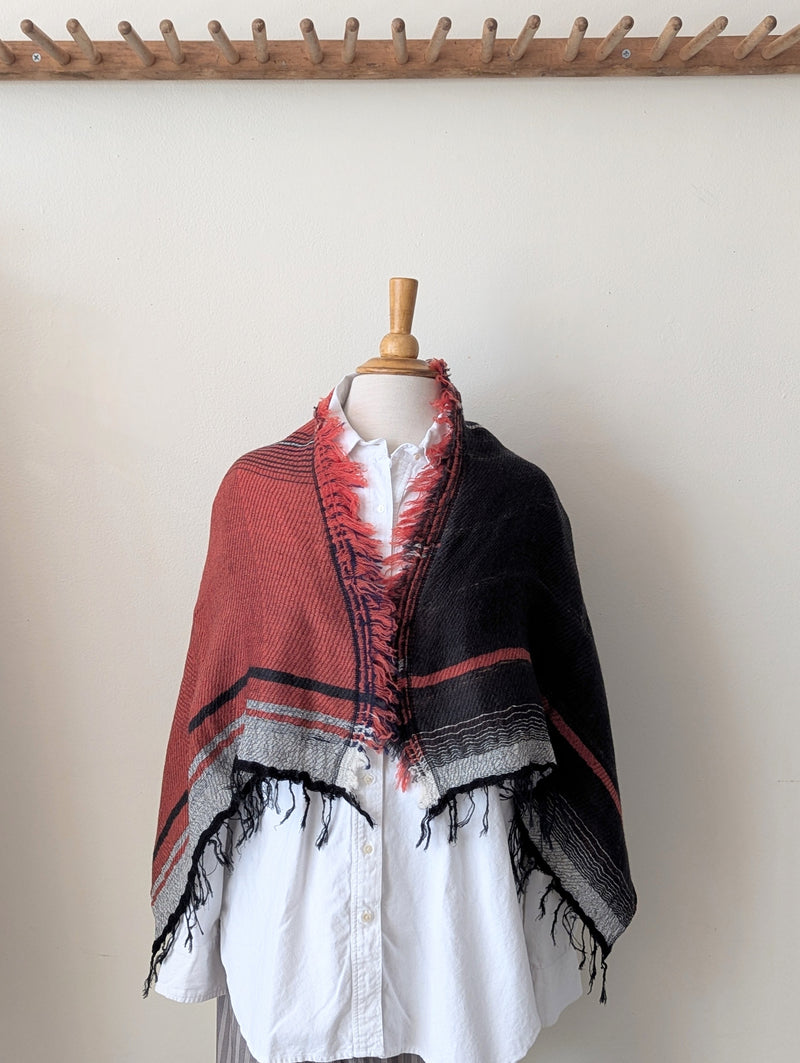 Mannequin wearing a red and black patterned shawl on a white background