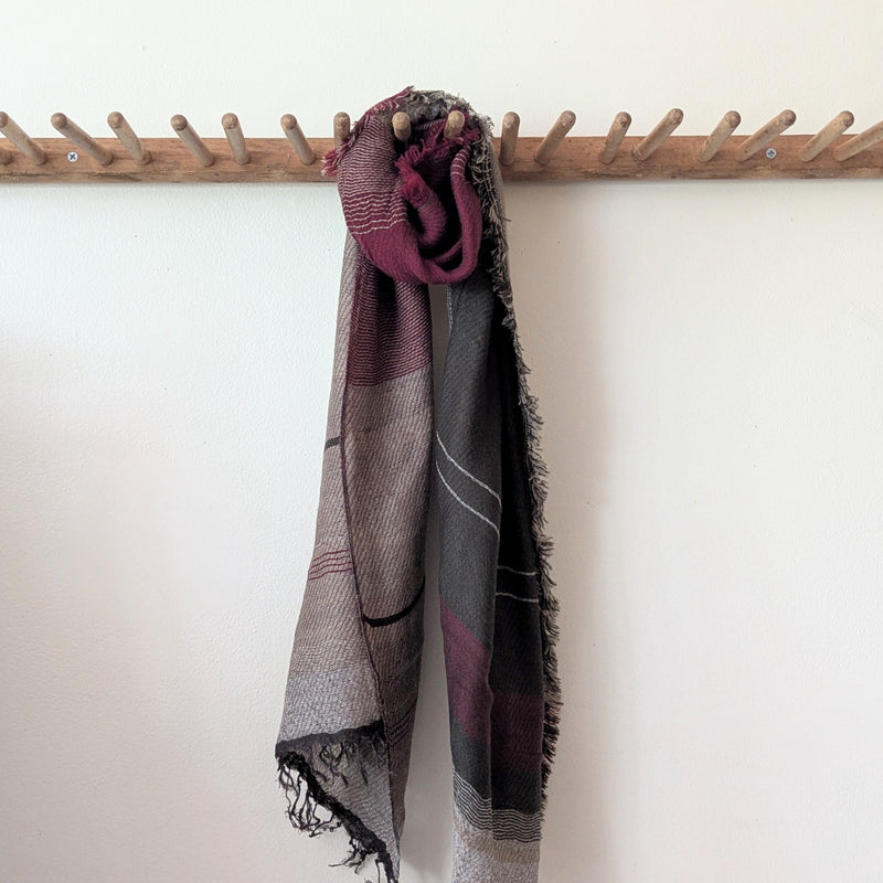 Patterned scarf draped over a wooden coat rack against a white wall