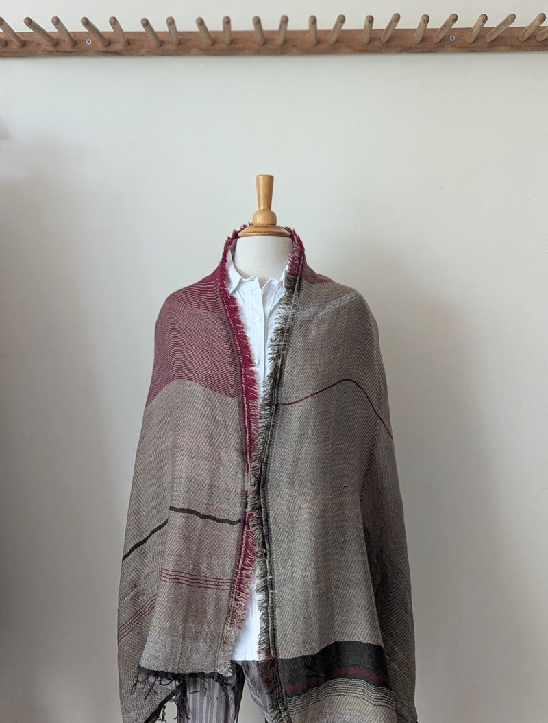 Patterened shawl draped over a mannequin against a plain background