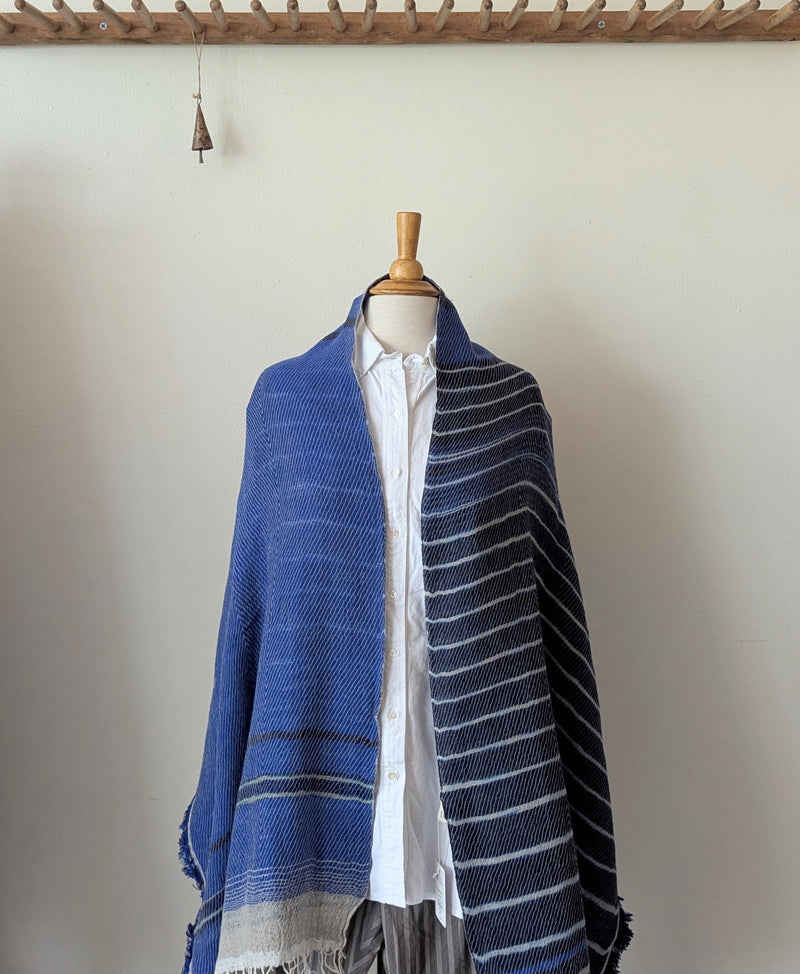 Mannequin wearing a blue striped shawl against a plain background